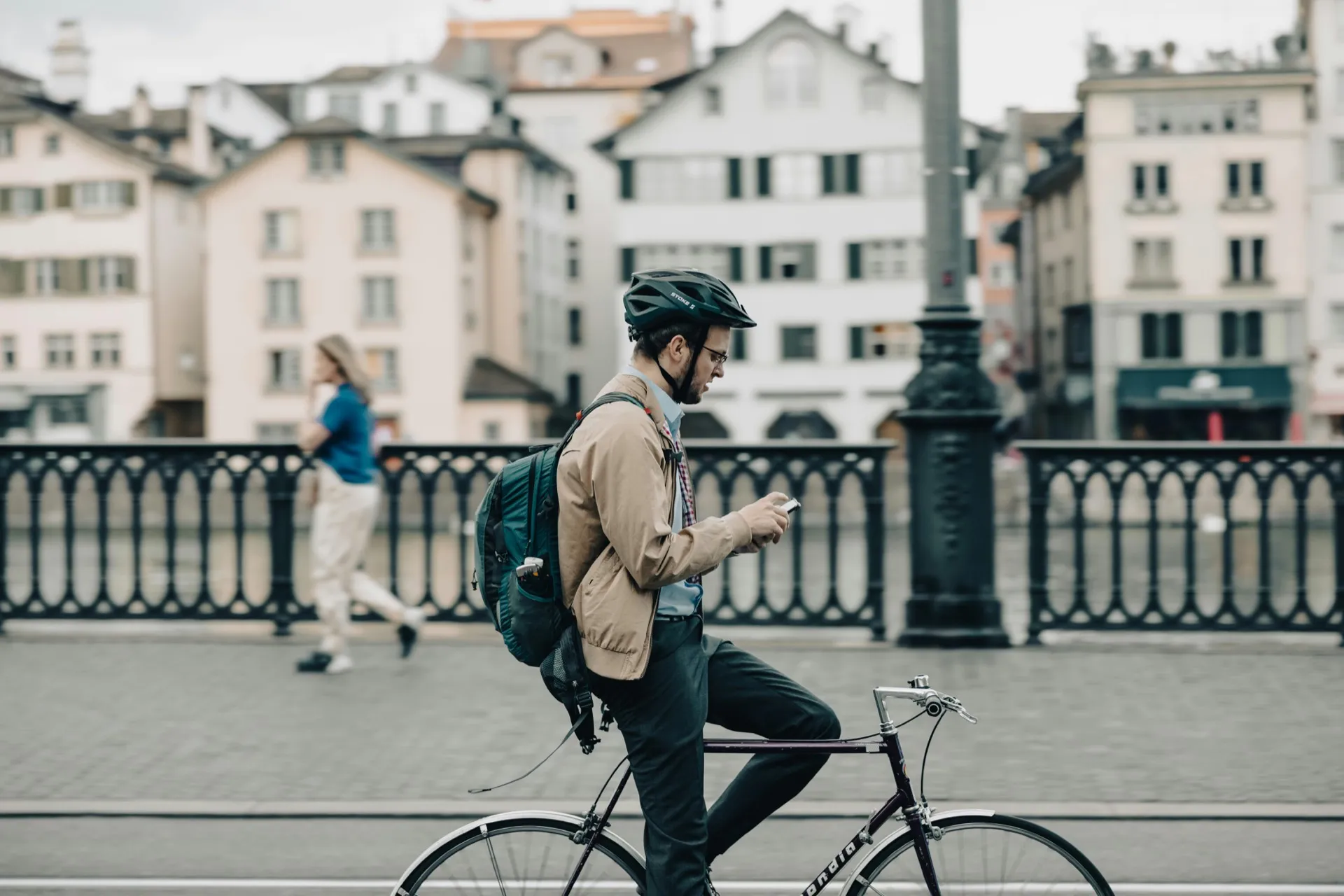 Cyclist commuting through a city while checking a phone, illustrating the time and effort workers invest in getting to the office